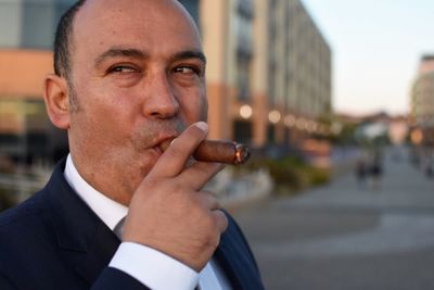 Businessman smoking cigar on road in city