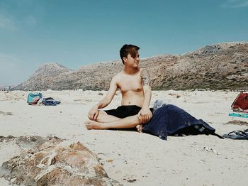Shirtless boy sitting at beach