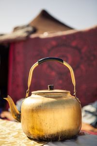 Close-up of gold colored tea kettle on table