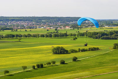 Paraglider flying over a rural landscape and with a swedish city