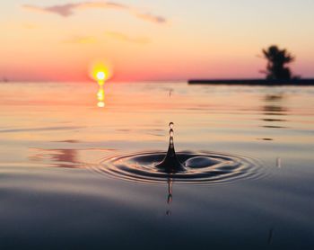 Close-up of splashing droplet in infinity pool against sky during sunset