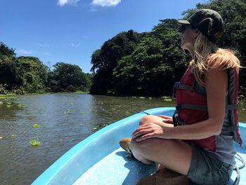 Woman sitting on boat in river against sky