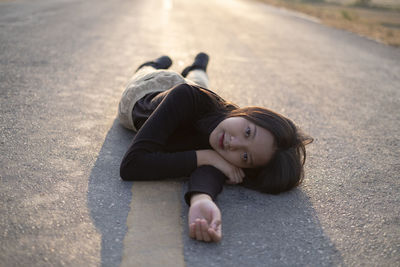 Portrait of girl lying down on road