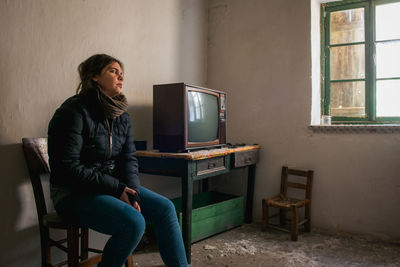 Young woman lonely in an abandoned ruined room with television. loneliness concept