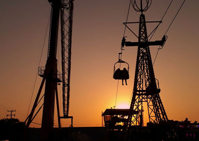 Low angle view of silhouette ski lifts against sky during sunset