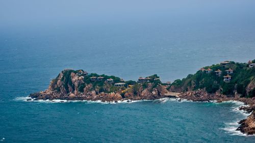 Rock formations in sea against blue sky