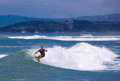 Man surfing in sea against sky