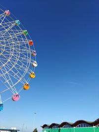 Low angle view of ferris wheel against clear blue sky