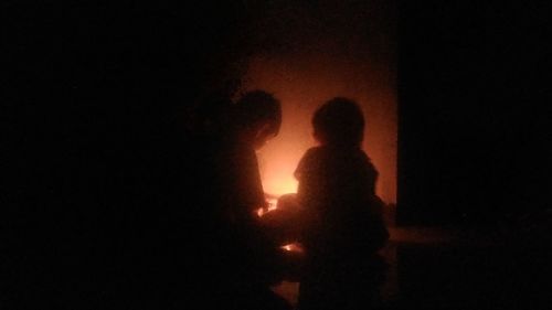 Silhouette people standing against illuminated light at night