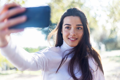 Close-up of smiling young woman taking selfie outdoors