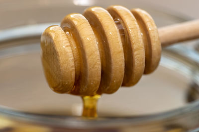 Garlic with honey in a glass jar on the kitchen counter with a wooden honey stick.