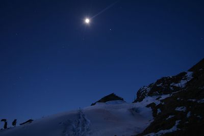 Low angle view of snowcapped mountains against clear blue sky at night