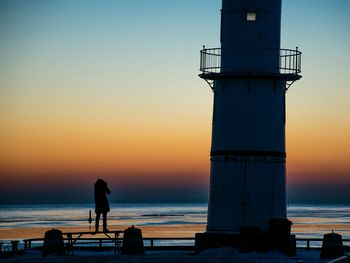 Silhouette people standing on beach against clear sky during sunset
