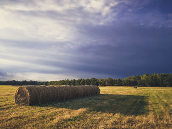 Hay bales on field against sky