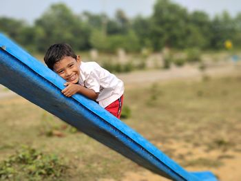 Young boy posing on a baby slide with green blur background. cute smiling 5 years teen boy portrait