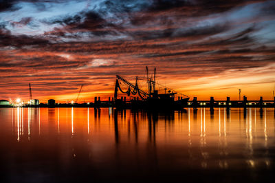 Shrimp boat at the pier at sunset with lights in the background