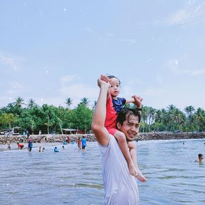 People enjoying at beach against sky