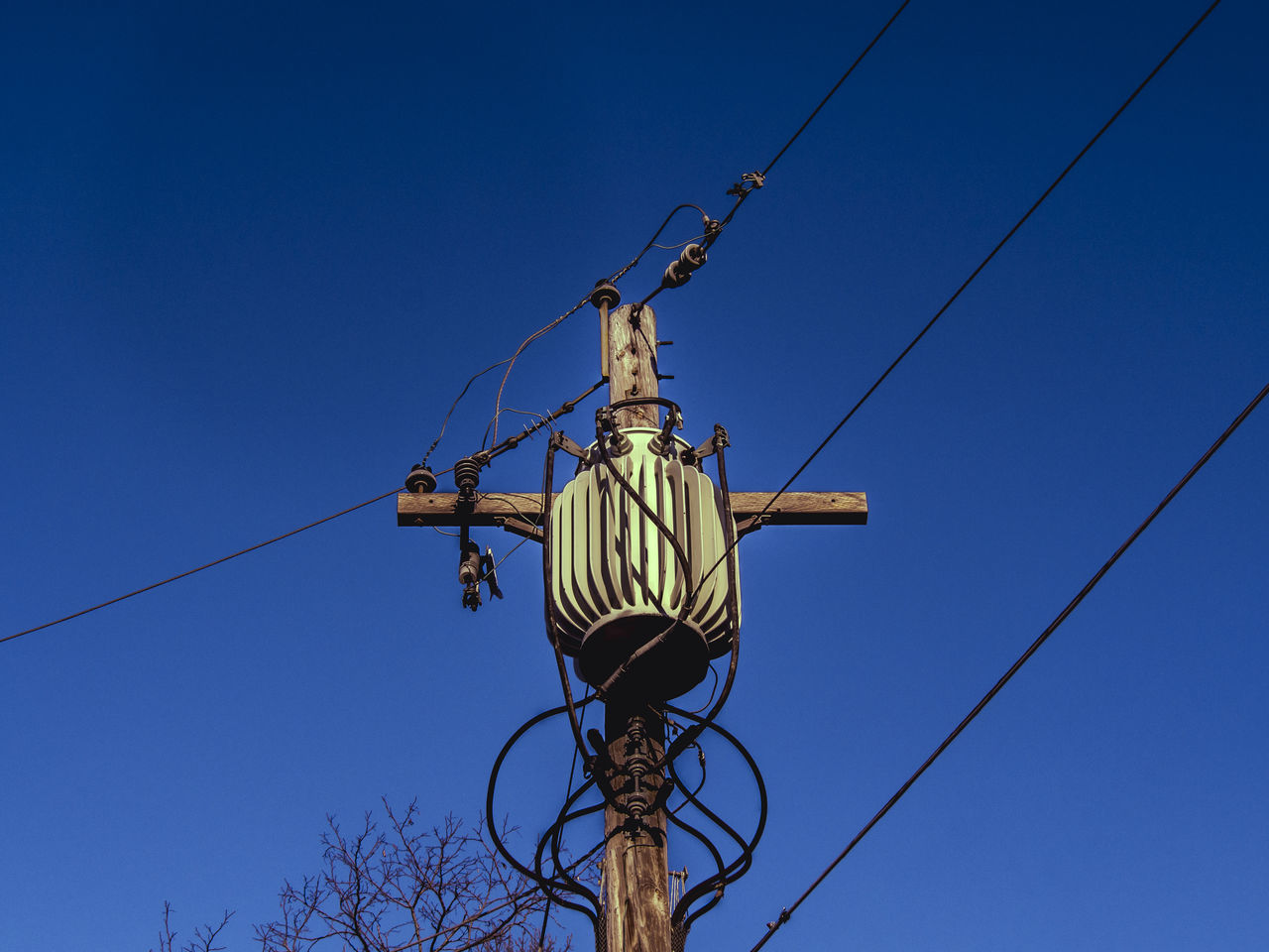 Low angle view of electricity pole against blue sky