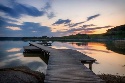 Pier over lake against sky during sunset