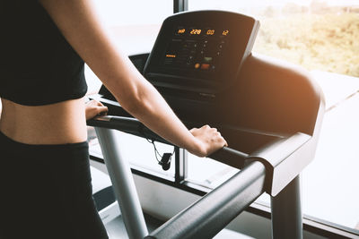 Midsection of woman on treadmill in gym