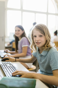 Portrait of girl with blond hair sitting at desk in computer classroom