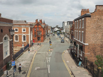 Vehicles on road amidst buildings in city against sky