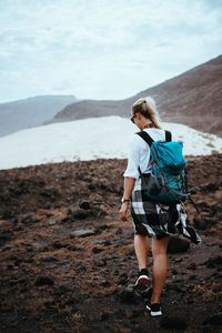 Rear view of woman standing on rock against sky