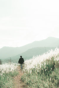 Rear view of man on field against sky