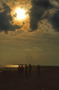 Silhouette people on beach against sky during sunset