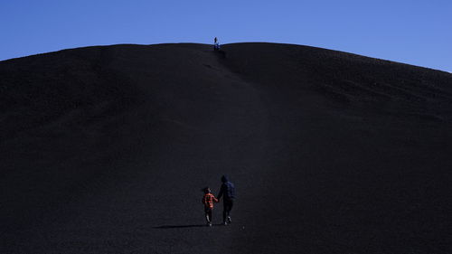 People walking on mountain against clear sky