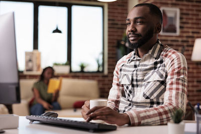 Young man using laptop while sitting on table