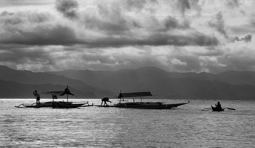 Boat sailing in sea against cloudy sky