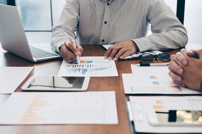 Midsection of business colleagues working at desk in office