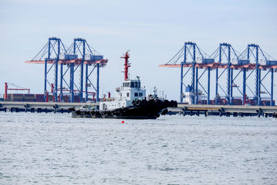 Cranes at commercial dock against sky