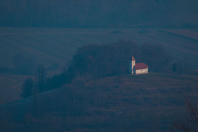 House amidst trees and buildings against sky