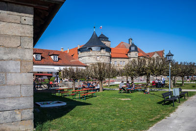 Group of people in front of buildings against blue sky