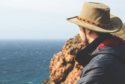 Rear view of man standing by sea against clear sky