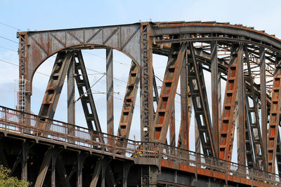 Low angle view of rusty bridge against sky