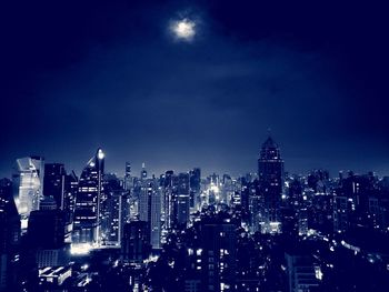 Illuminated buildings in city against sky at night