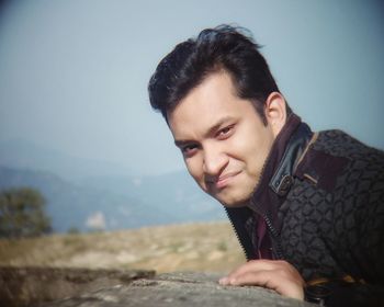 Portrait of young man looking away against sky