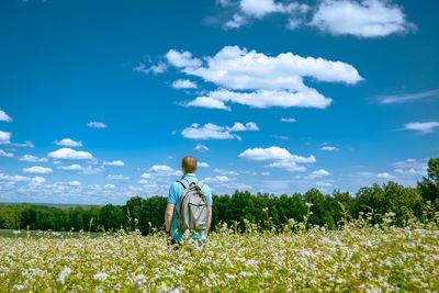 Rear view of man standing on field against sky