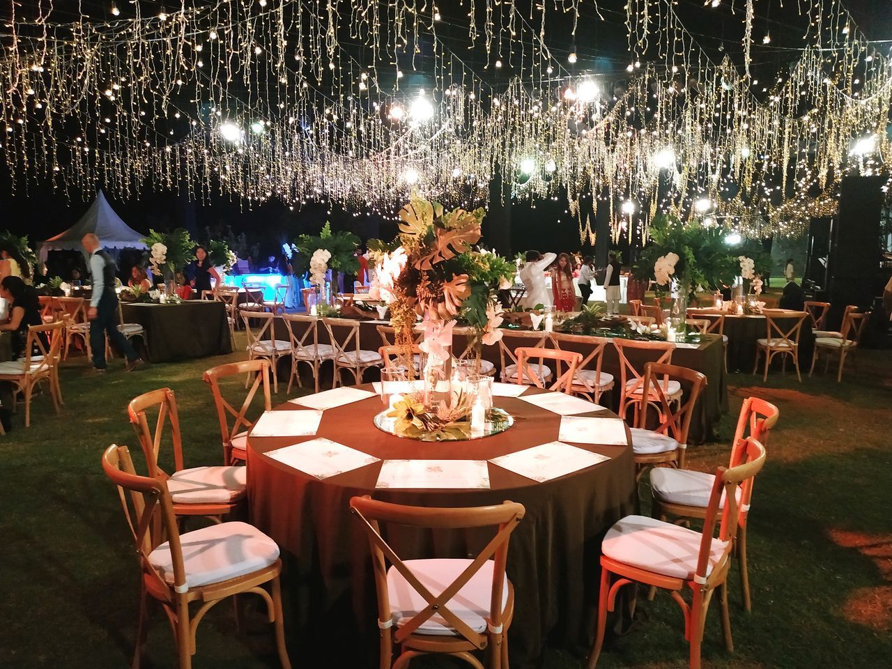 EMPTY CHAIRS AND TABLES AT ILLUMINATED RESTAURANT