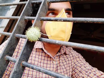 Young man wearing mask looking through window
