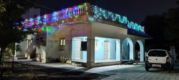 Illuminated road by buildings in city at night