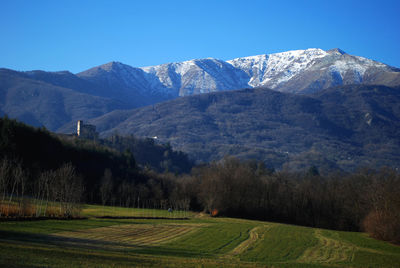 Scenic view of field and mountains against clear sky