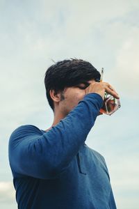 Portrait of young man standing against sky