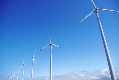 Low angle view of wind turbine against clear blue sky