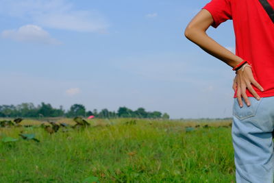 Midsection of woman standing on field against sky