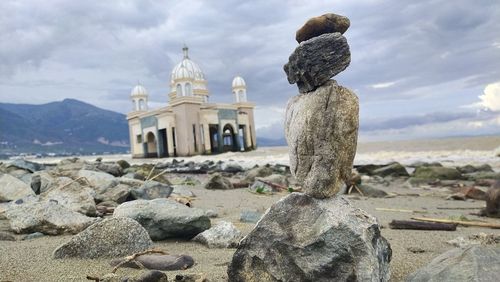 Rock stackin in talise beach with the floating mosque in behind the rock. palu, indonesia