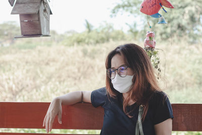 Woman wearing mask while sitting on bench